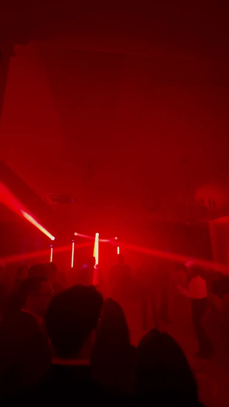 Fasci di luce blu e verdi che attraversano la foschia sopra la pista da ballo durante il live