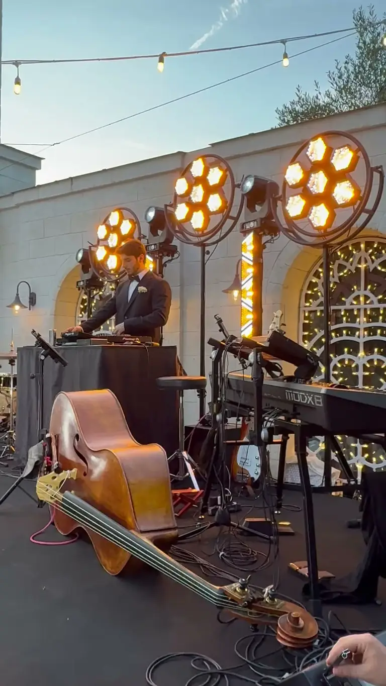 Terrazza allestita al tramonto con fari a luce calda su piantane e postazione musicale pronta per il live
