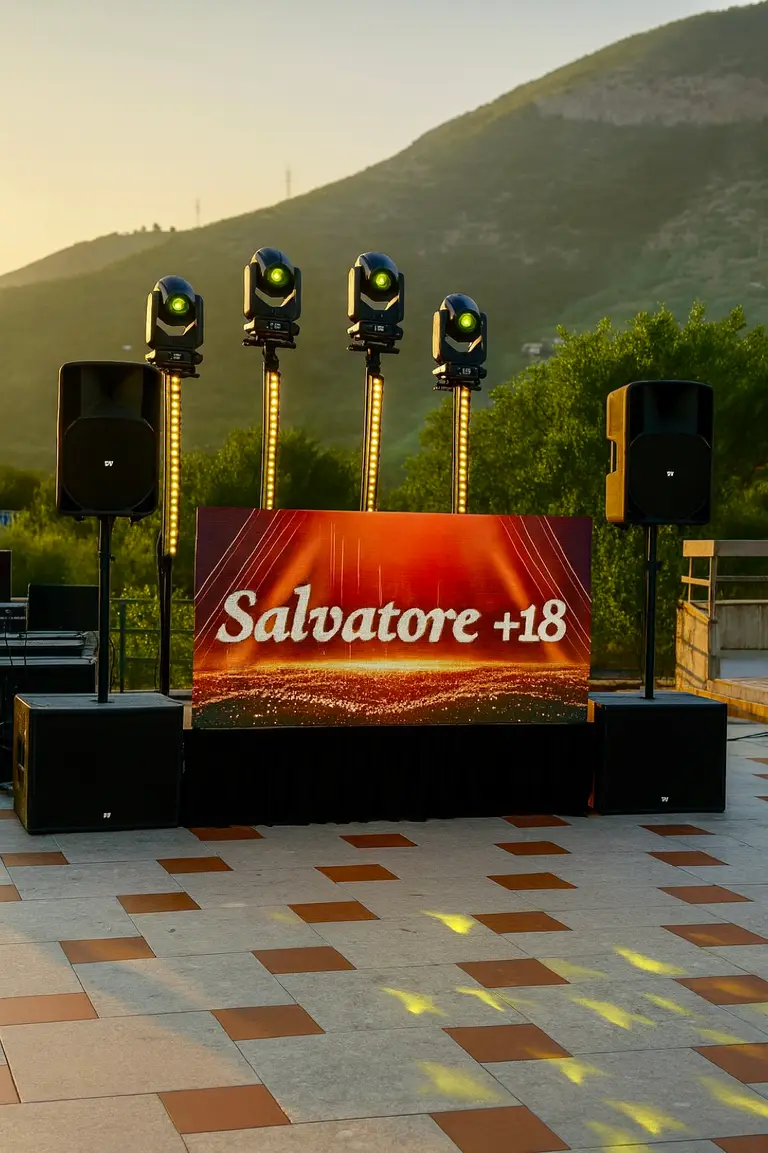 Ledwall all'aperto al tramonto con teste mobili su piantane e diffusori ai lati