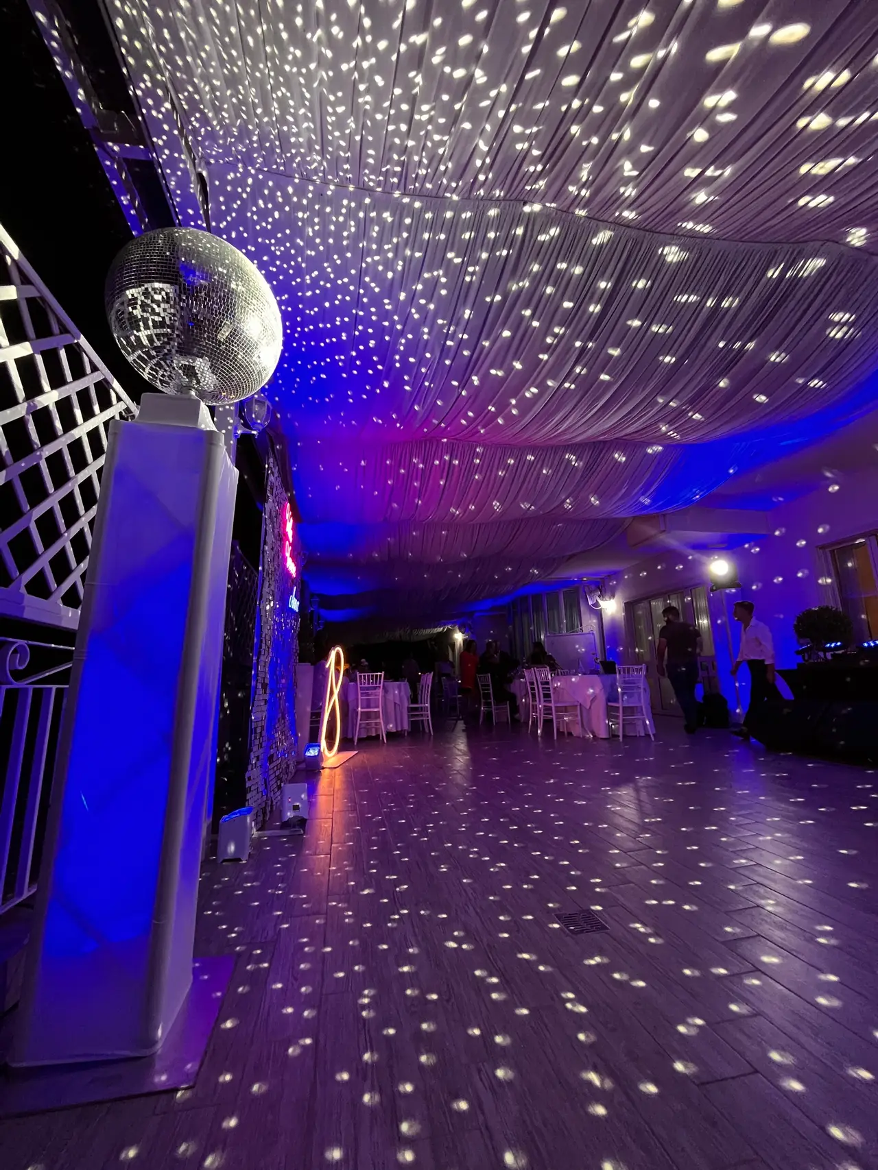 Sfera specchiata che proietta punti di luce sul soffitto drappeggiato di una sala