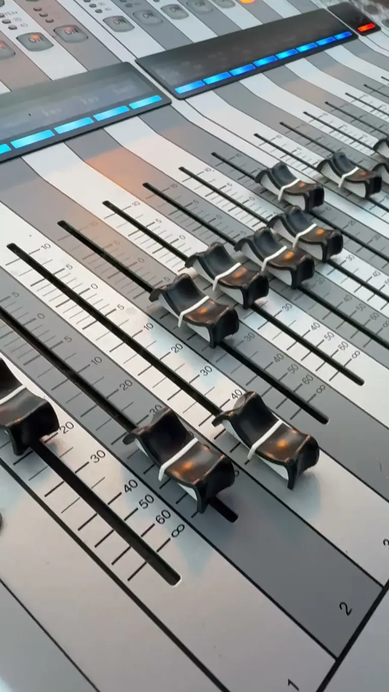 Primo piano dei fader di un mixer digitale in regia durante un evento