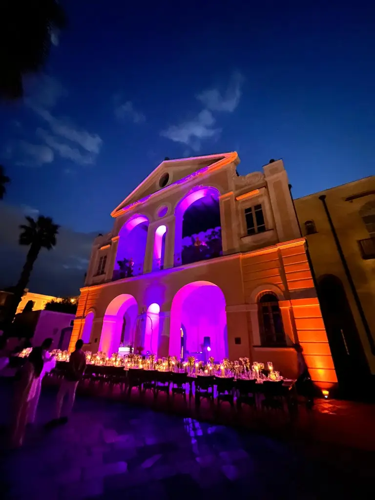 Villa storica illuminata con uplight viola e ambra durante un ricevimento serale
