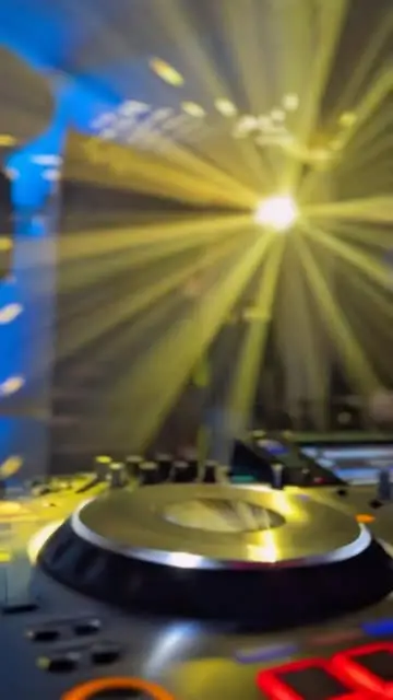 Consolle DJ tra fasci di luce dorati durante una serata
