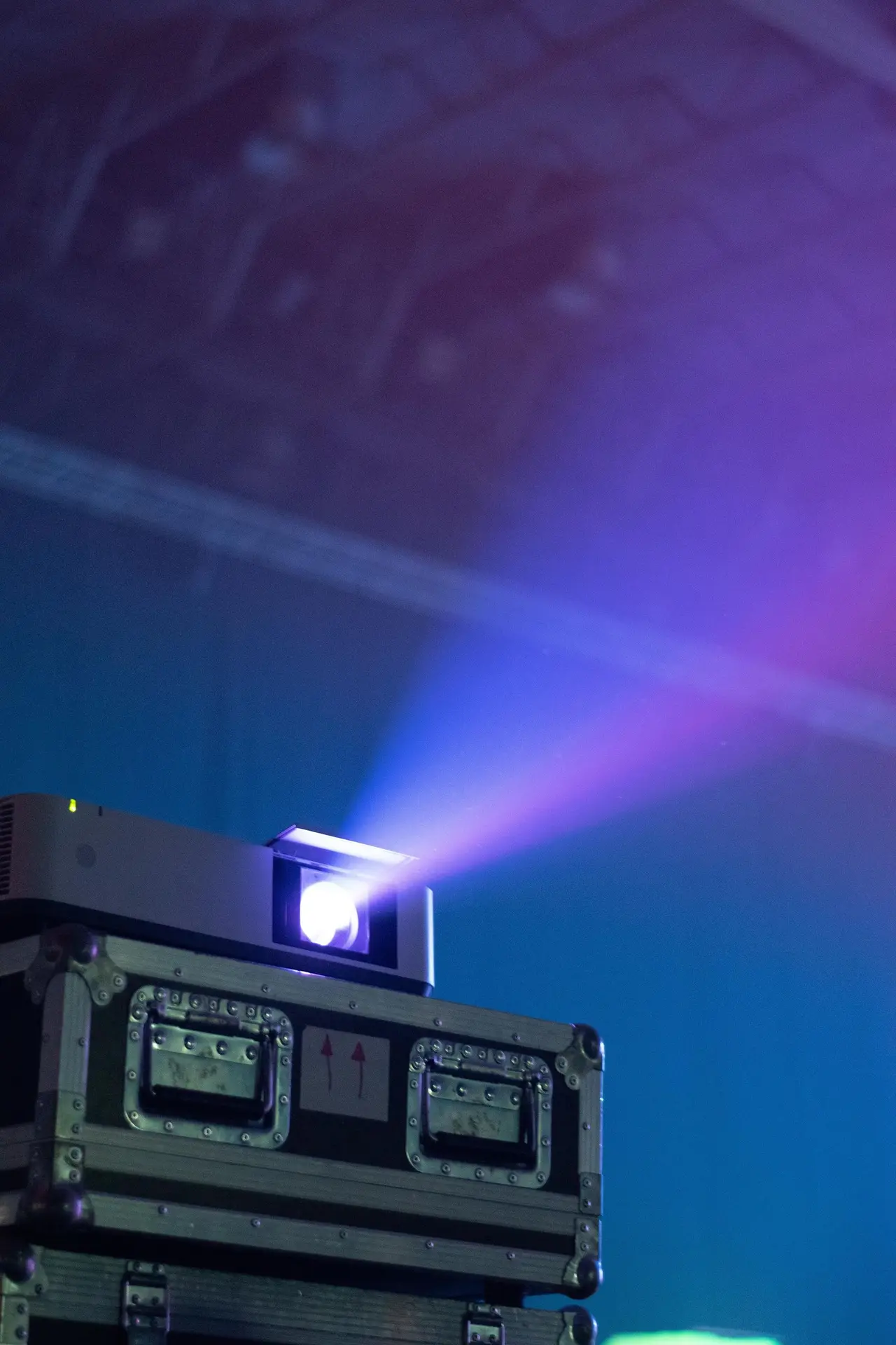 Videoproiettore su flight case che proietta un fascio di luce in una sala buia